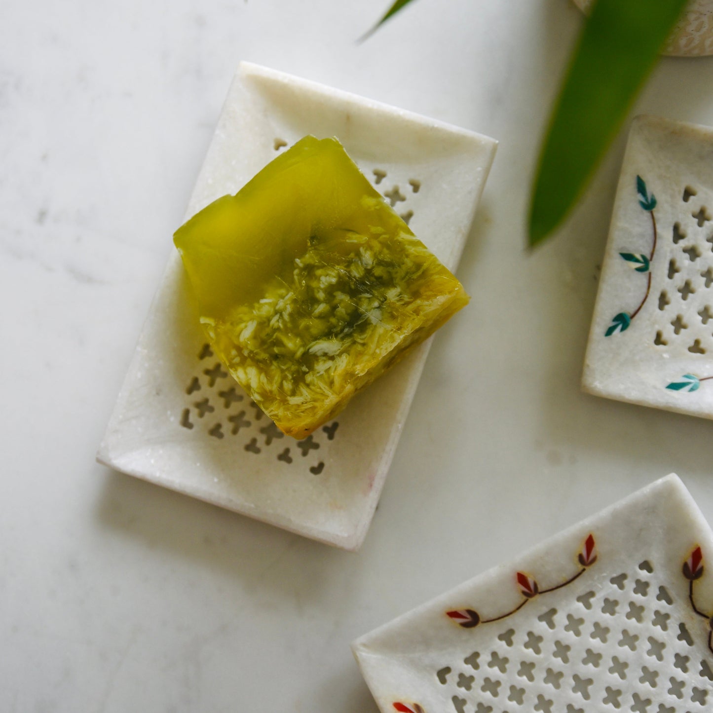 Decorative ceramic trays with a green leafy item on a marble surface