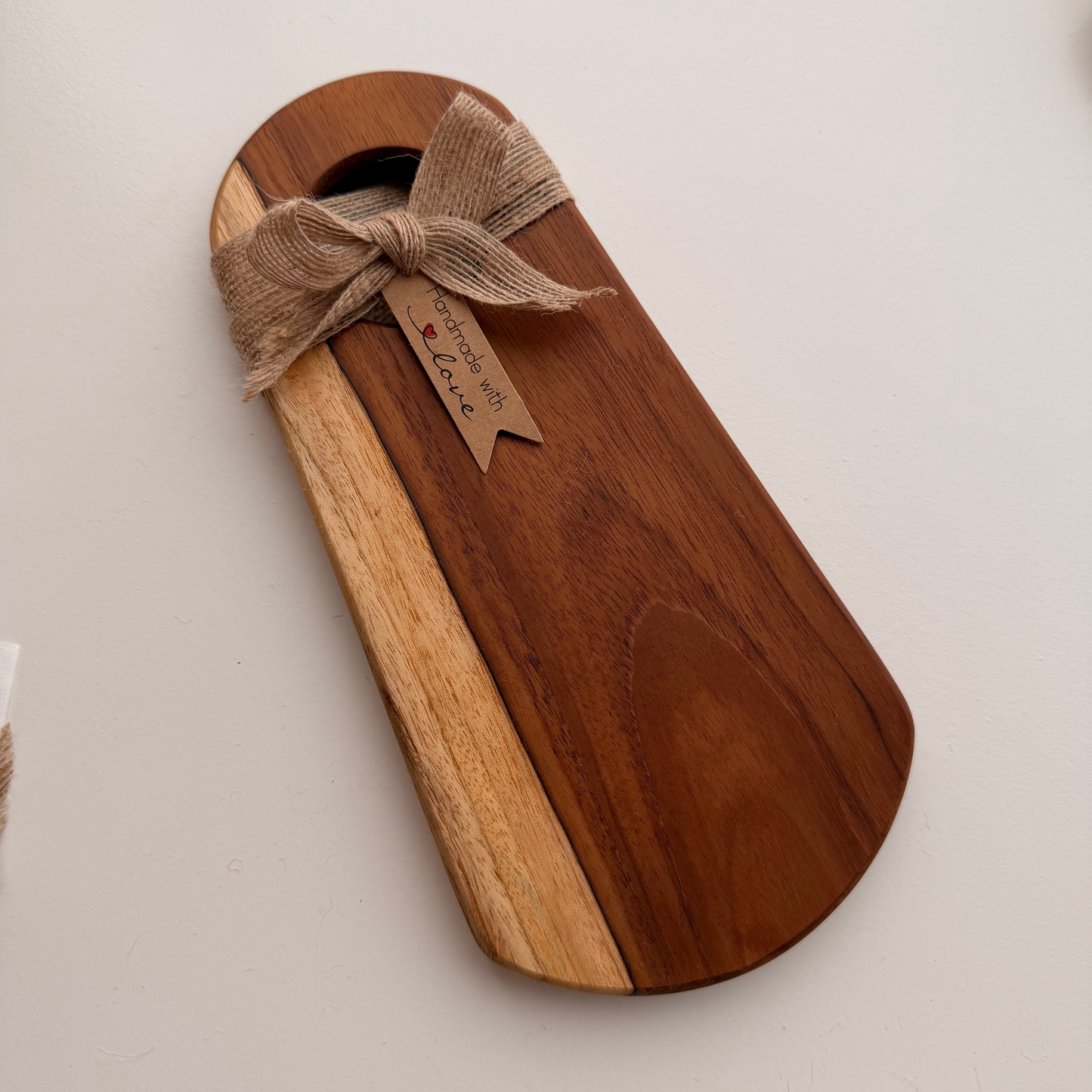 Wooden cutting board with a burlap bow on a light gray background