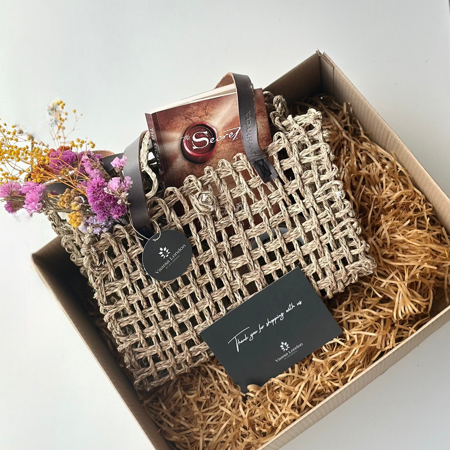 Woven handbag with flowers and a card in a box on a white background