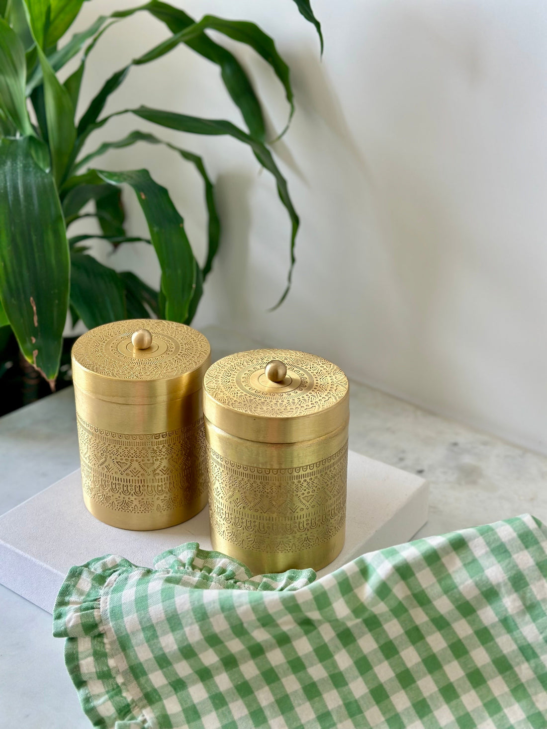 Minimalist gold brass kitchen storage canisters for coffee and sugar on a white marble background