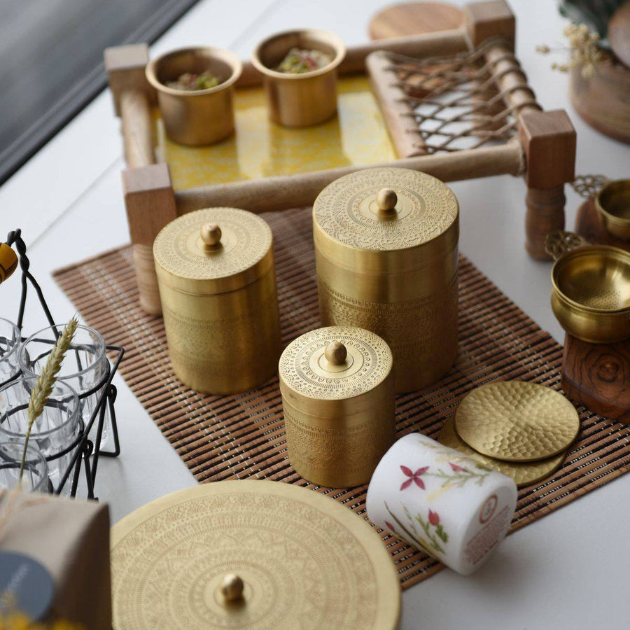 Vaarsa brass jars, masala dabba, Charpayi tray and hammered brass coasters on a table