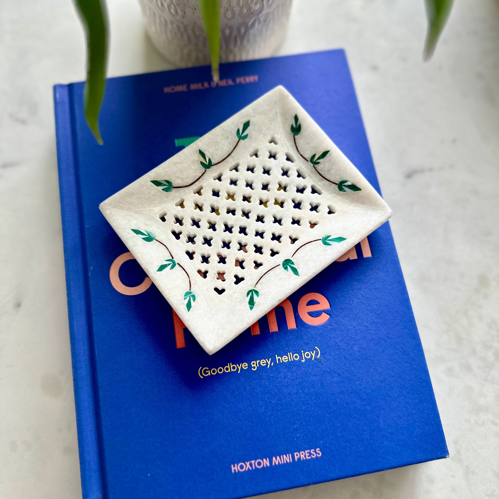 Decorative ceramic tray with floral patterns on a blue book
