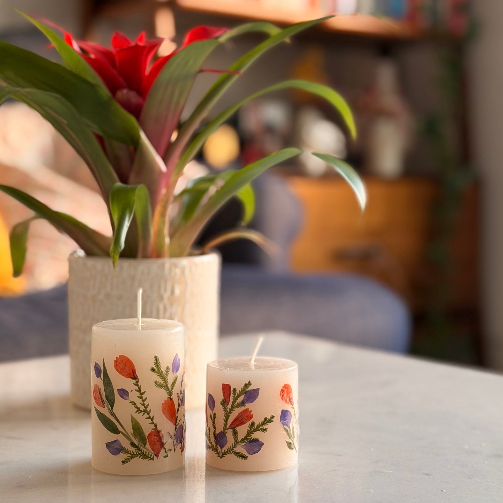 Decorative candles with floral designs on a table in a cozy room.
