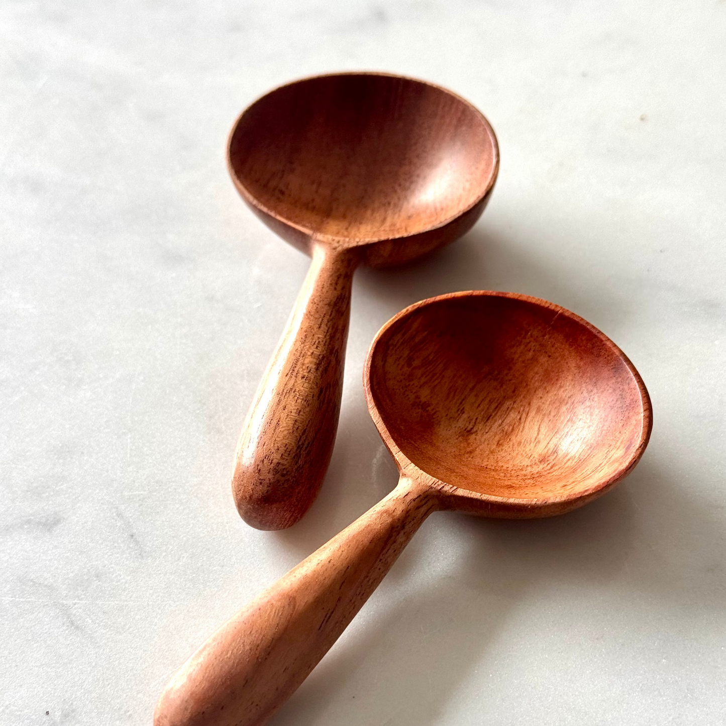 Two wooden spoons on a light marble surface