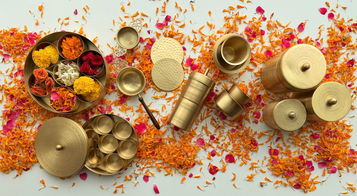 Brass objects on a table scattered with marigold and rose petals