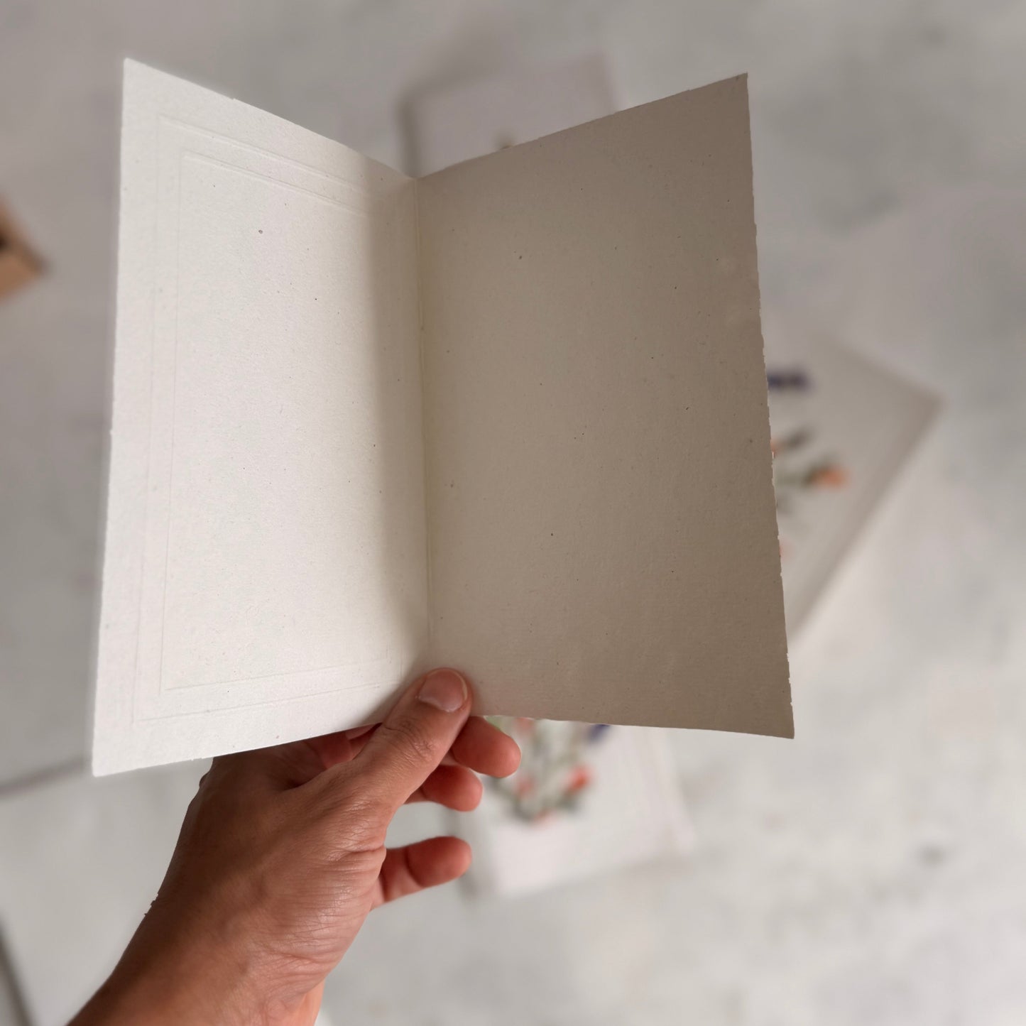 Hand holding an open notebook with lined pages on a light background