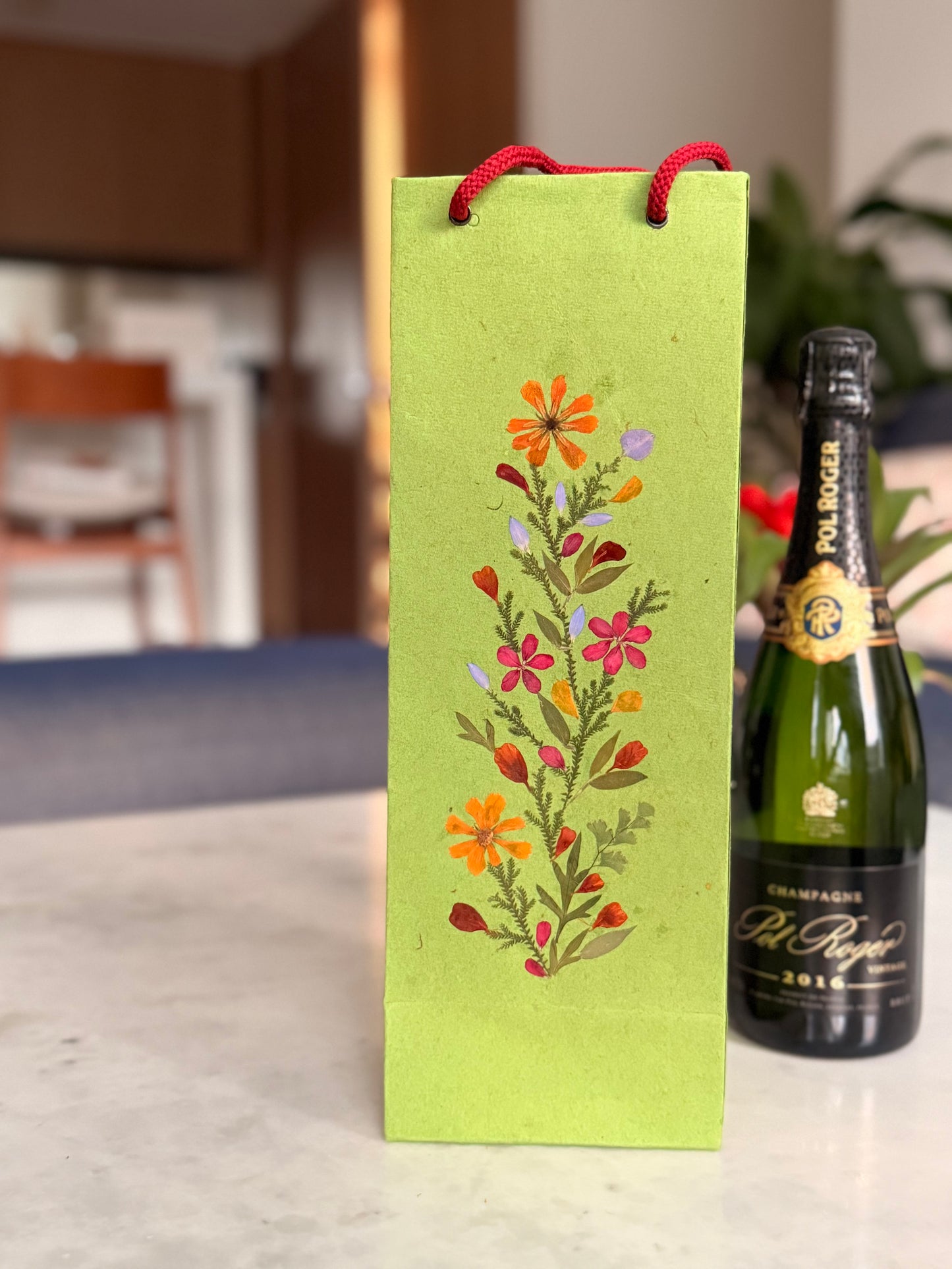 Green floral bottle wine gift paper bag with a wine bottle on a blurred background
