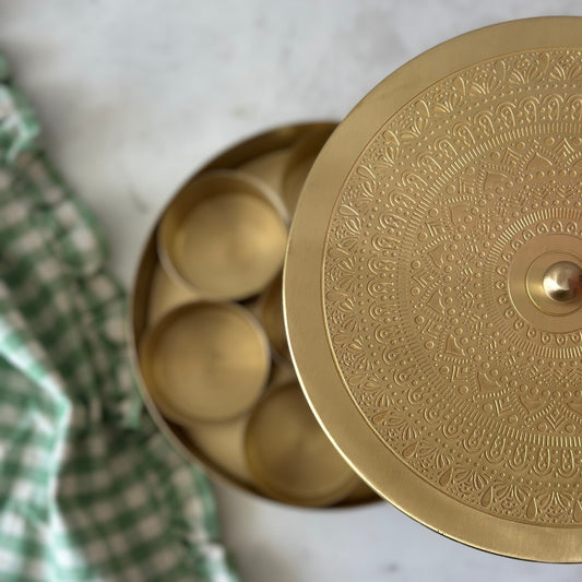 Opened brass masala dabba showing seven spice compartments